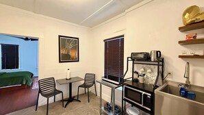 A compact kitchen with a dining area, a microwave, a toaster, and a sink. - escondido studio: Walk to Restaurants + Bars (Houston)