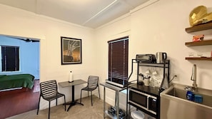 A compact kitchen with a dining area, a microwave, a toaster, and a sink. - Montrose Studio | World Cup & Fan Fest Stay (Houston)