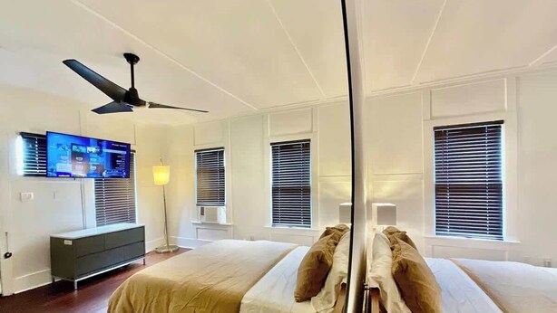 A bedroom with a bed, a TV, a ceiling fan, and a bedside table. - escondido studio: Walk to Restaurants + Bars (Houston)