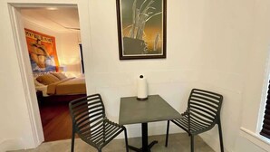 A small room with a table and two chairs, a poster on the wall, and a door leading to another room. - escondido studio: Walk to Restaurants + Bars (Houston)