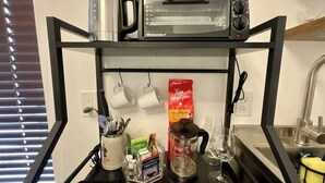 A kitchen counter with a coffee maker, a toaster, and a coffee bag. - escondido studio: Walk to Restaurants + Bars (Houston)