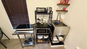 A compact kitchenette with a stove, microwave, toaster, kettle, and sink. - escondido studio: Walk to Restaurants + Bars (Houston)