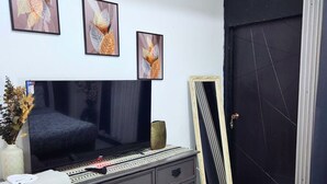 Une chambre à coucher avec un lit, une commode, un téléviseur et des œuvres d’art encadrées accrochées au mur.