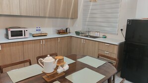 A modern kitchen with wooden cabinets, a microwave, a kettle, and a refrigerator.