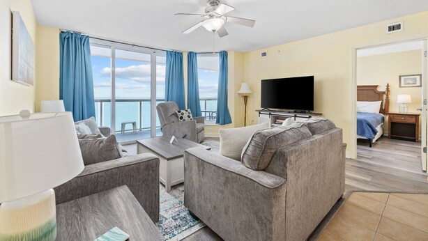 A modern hotel room with a balcony, a flat-screen TV, a sofa, and a desk. - Stay Elevated – North Myrtle Beach 3BR Penthouse at Malibu Pointe Resort (North Myrtle Beach)