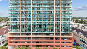 A multi-story hotel with numerous balconies and a parking garage below. - Stay Elevated – North Myrtle Beach 3BR Penthouse at Malibu Pointe Resort (North Myrtle Beach)