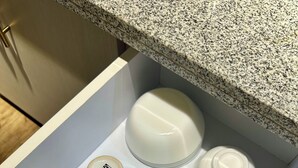 Eine Küchenschublade mit verschiedenen weißen Keramiktassen und einer weißen Teekanne.