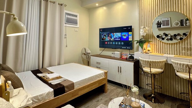 Ein Hotelzimmer mit einem Bett, einem Schreibtisch, einem Fernseher, einem Spiegel und einer kleinen Sitzecke.