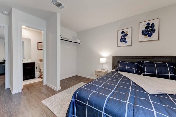 A bedroom with a bed, a nightstand, a lamp, and two wall art pieces.