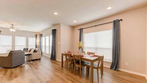 Un salon moderne avec un canapé, une table à manger et des chaises, ainsi qu’un ventilateur de plafond.
