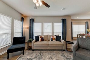 A living room with a sofa, two armchairs, a coffee table, and a dining area with a table and chairs.