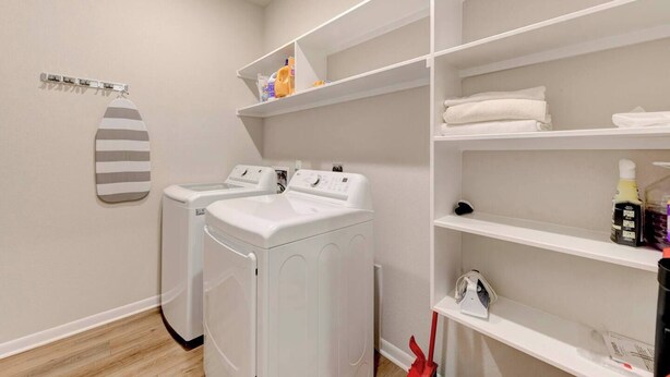 Un espace buanderie comprenant deux machines à laver, un étendoir et des étagères avec des serviettes et des articles de toilette.