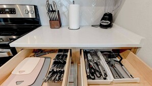 Un plan de travail de cuisine avec une cuisinière, un bloc à couteaux, un porte-essuie-tout et un mixeur.
