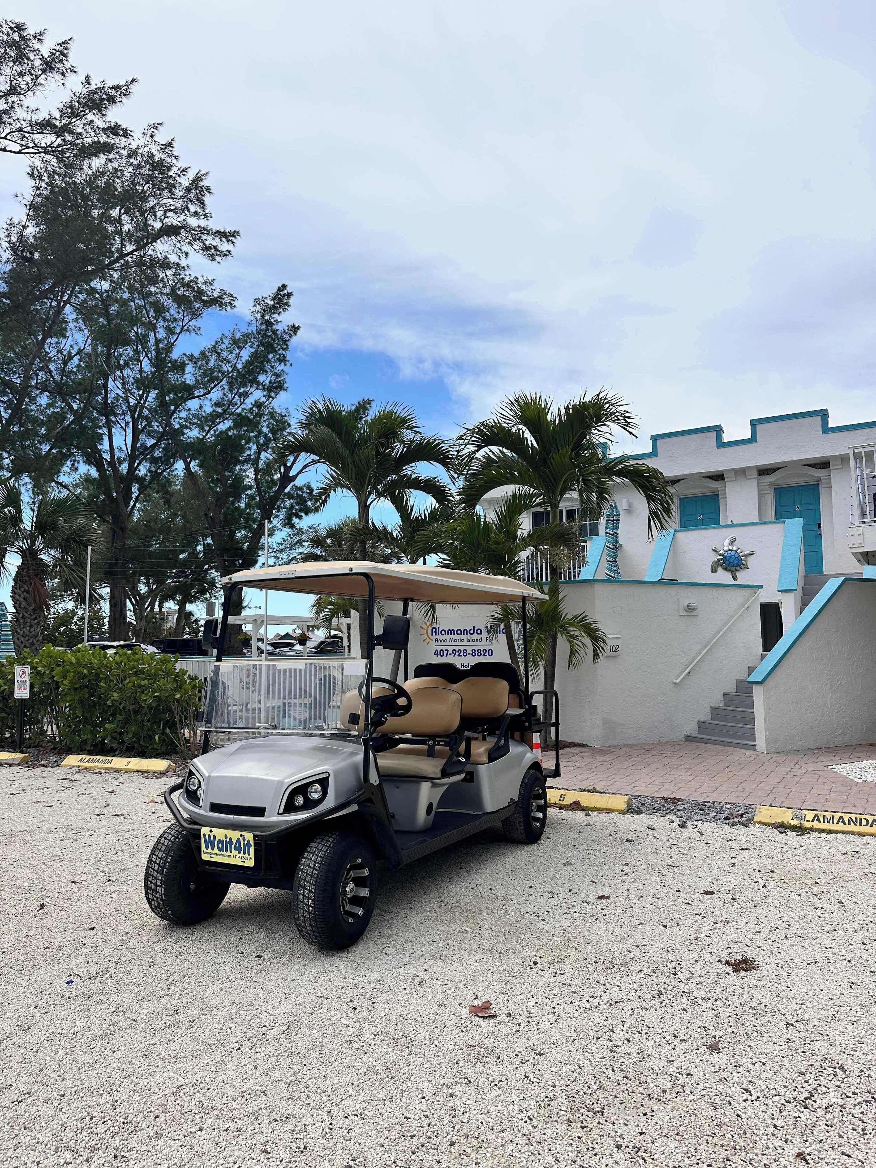 A golf cart parked in a gravel area with a building in the background.