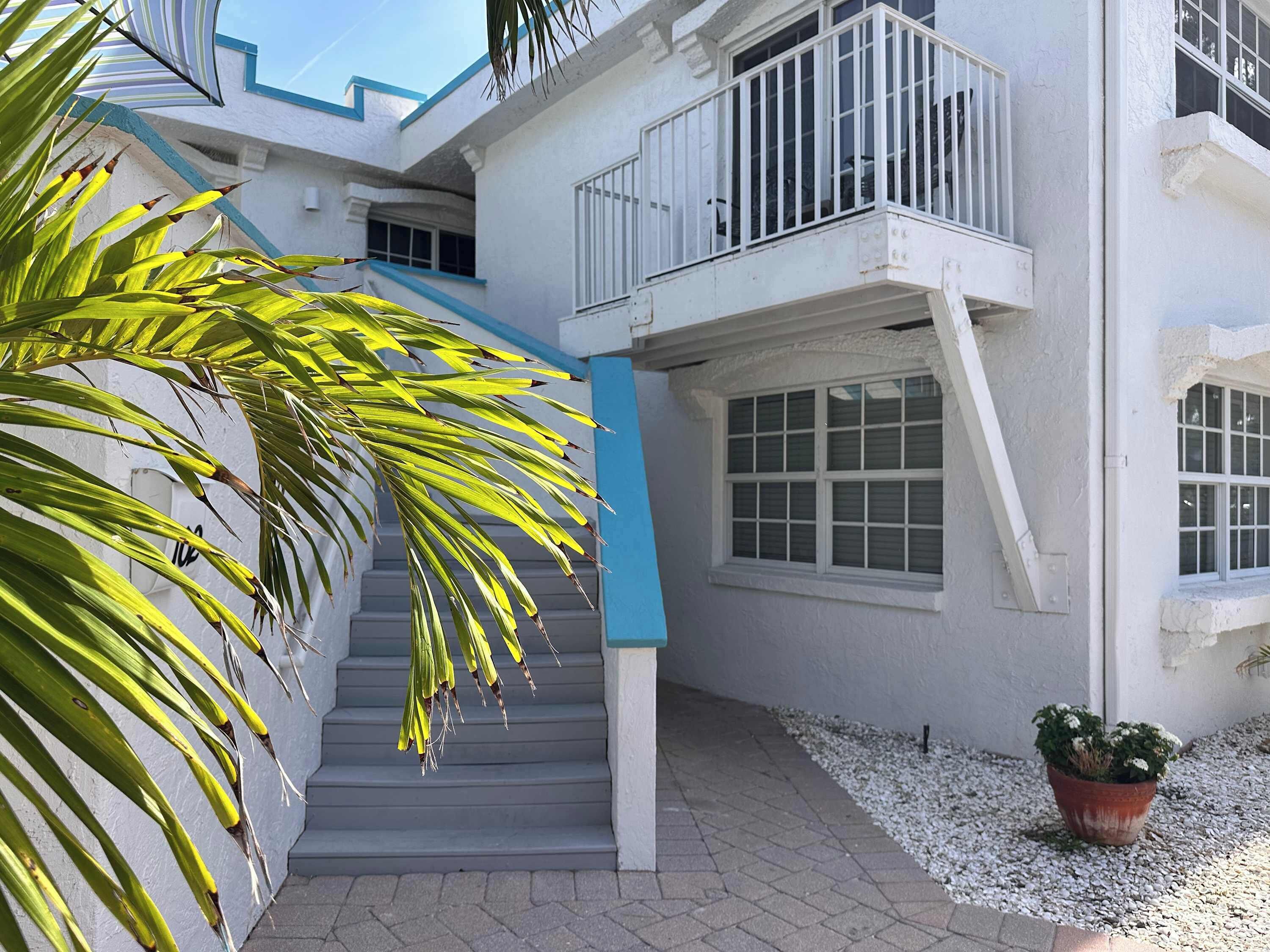 A white building with a blue staircase and a balcony.