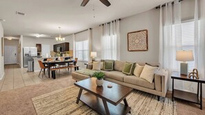 A modern living room with a sofa, coffee table, and dining area.