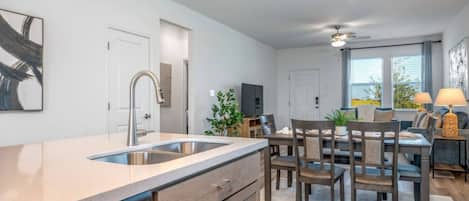 A modern kitchen with a dishwasher, a dining area with a table and chairs, and a ceiling fan.