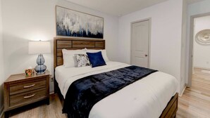 A bedroom with a bed, a nightstand, a lamp, a painting, and a door. - 4BR Corporate Stay in Hutto (Hutto)