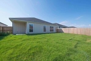 A single-story house with a covered patio, a fenced backyard, and a clear sky. - Workers Heaven in Lorena (Austin)