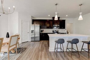 A modern kitchen with a central island, stainless steel appliances, and bar stools.