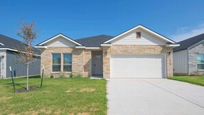 A residential house with a garage, stone facade, and a well-maintained lawn.