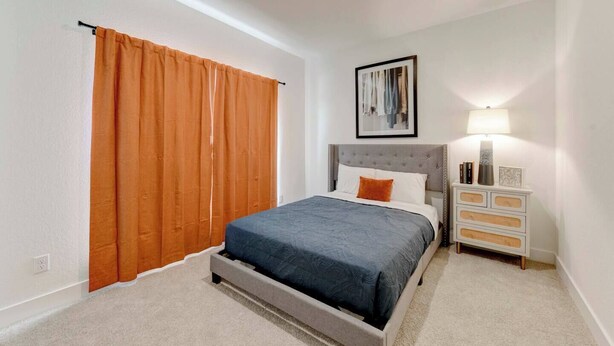 Un dormitorio con una cama, una mesita de noche, una lámpara y un cuadro en la pared.