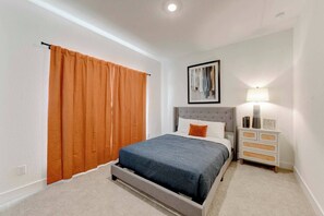 A bedroom with a bed, a nightstand, a lamp, and a framed picture on the wall. - Workers Heaven in Lorena (Austin)