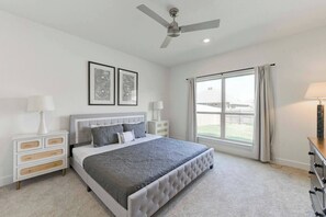 A bedroom with a bed, bedside tables, a ceiling fan, and a large window.