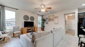 A living room with a sofa, TV, and a ceiling fan.