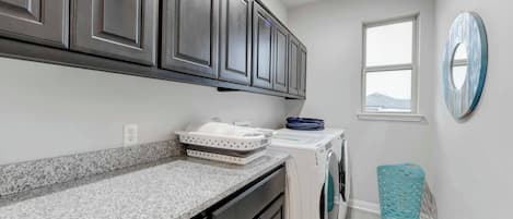 A laundry room with a washing machine, a dryer, and a countertop with a basket.