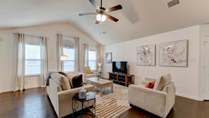 A spacious living room with a ceiling fan, a flat-screen TV, and two sofas. - North Austin Corporate-Ready 3BR (Austin)