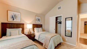 A bedroom with two beds, a nightstand, a lamp, a closet, and a mirror. - North Austin Corporate-Ready 3BR (Austin)