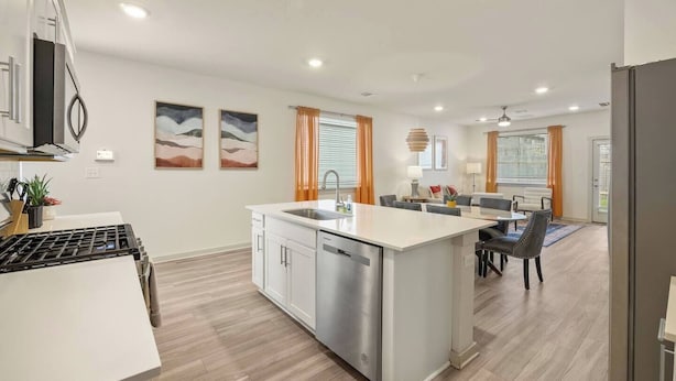 Een moderne keuken met een centraal eiland, een eethoek met stoelen en een zithoek met een bank en lamp.