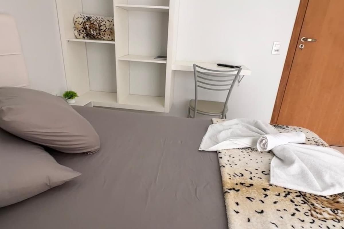 A bedroom with a bed, a chair, a wardrobe, and a door.
