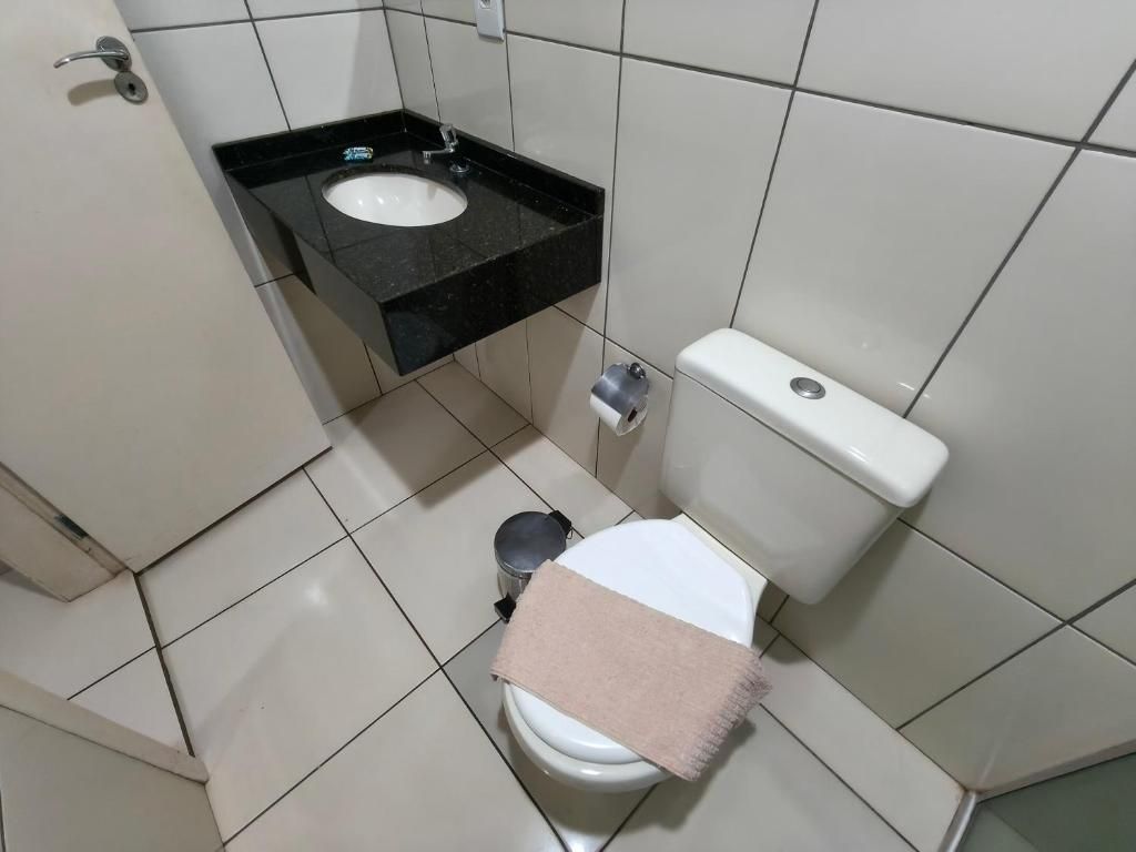 A small bathroom with a toilet, a sink, and a trash can.