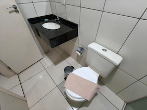 A small bathroom with a toilet, a sink, and a trash can. - Hotel Vitória - Guaíra PR (Guaíra)