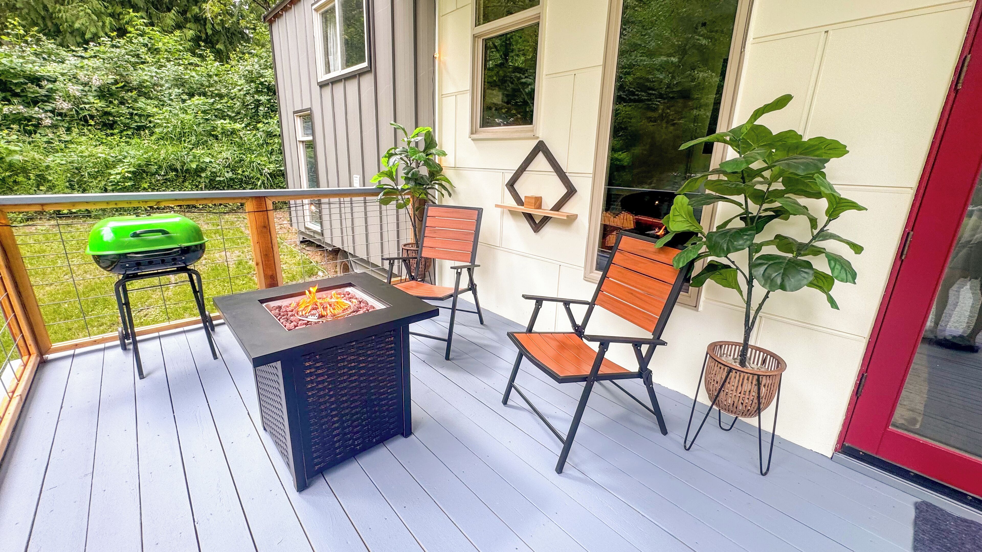 A deck with a built-in fire pit, outdoor seating, and a view of the surrounding greenery.