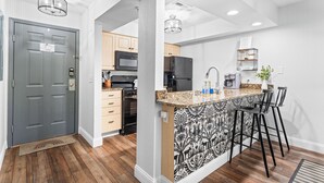 A modern kitchen with a central island, wooden cabinets, and a patterned backsplash. - Peaceful Golf Course View + Pool + Sunroom (Branson)