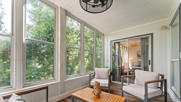 A room with large windows, a sofa, a chair, and a coffee table. - Peaceful Golf Course View + Pool + Sunroom (Branson)