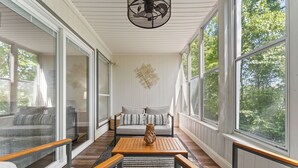 A sunlit room with a sofa, a wooden table, and a decorative vase. - Peaceful Golf Course View + Pool + Sunroom (Branson)