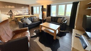 Una sala de estar con sofá, mesa de centro, televisor y comedor con mesa y sillas.