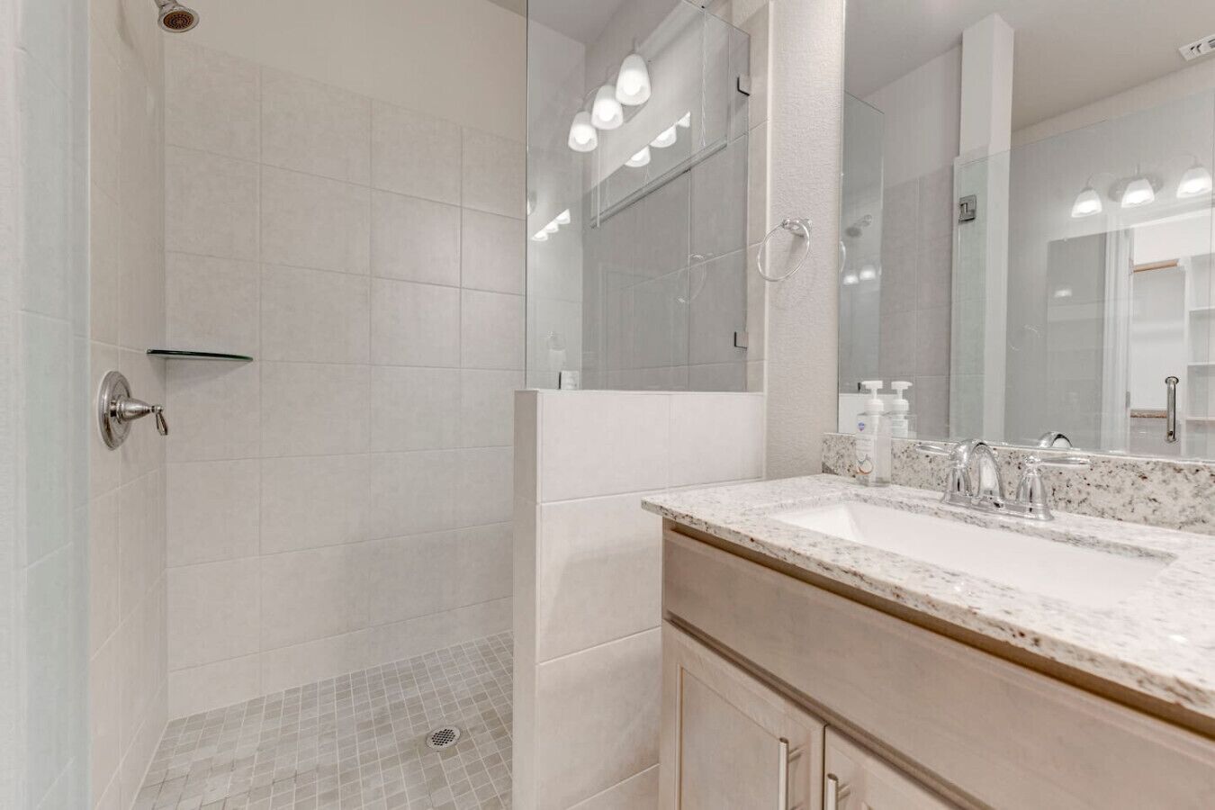 Un baño moderno con ducha a nivel, un espejo grande y una encimera de mármol.