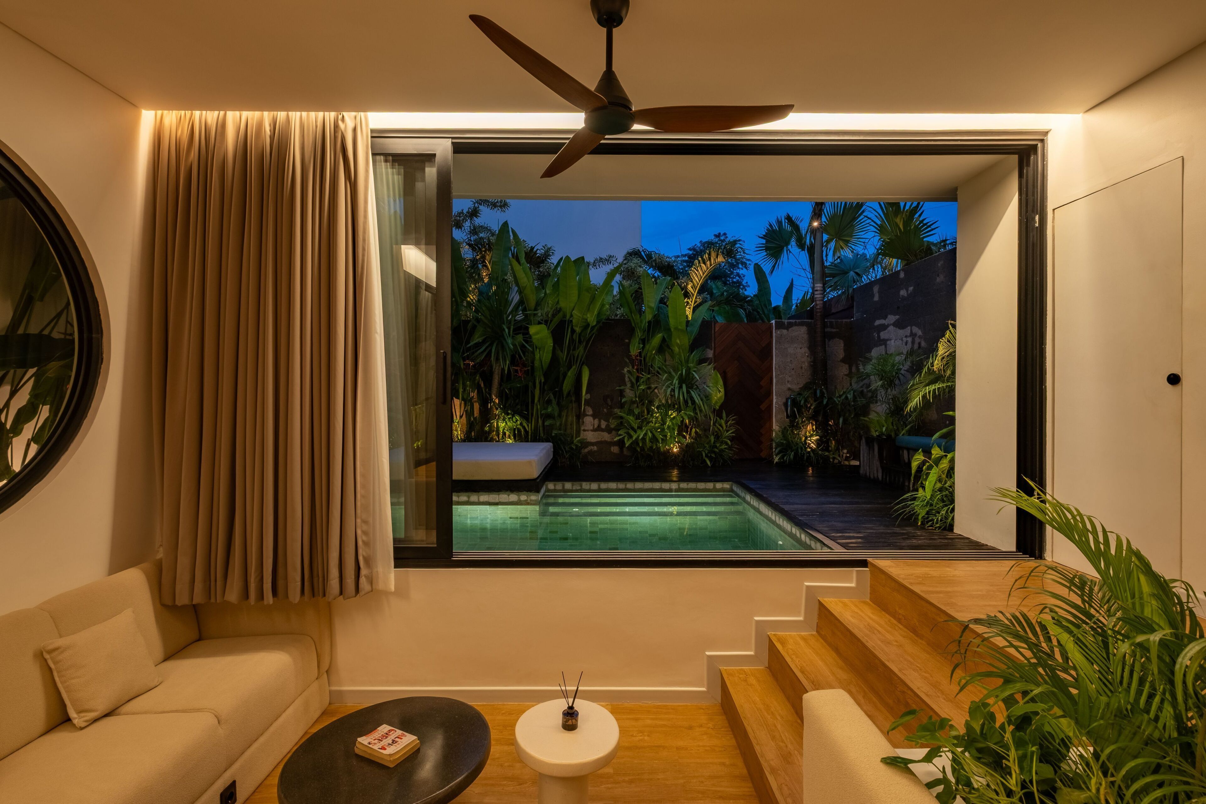 A modern interior with a view of a swimming pool, a ceiling fan, and a staircase leading to an outdoor area.