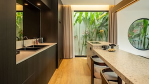 A modern kitchen with a wooden countertop, a built-in sink, and a dining area with chairs and a table. - Club Suma Villa Bingin (Pecatu)