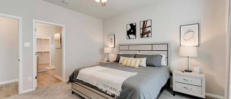 A bedroom with a bed, bedside tables, a ceiling fan, and artwork on the walls.