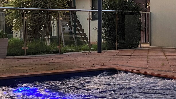 A swimming pool with water jets and a glass barrier.