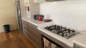 A modern kitchen with a gas stove, a toaster, and a refrigerator.