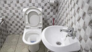 A bathroom with a toilet and a sink, both in white, with a checkered tile backsplash.