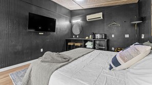 Une chambre à coucher comprenant un lit, une télévision, un four à micro-ondes et une commode.