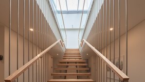 Een moderne trap met glazen balustrades en een dakvenster.